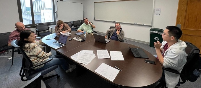 People seated at an oval table having a discussion